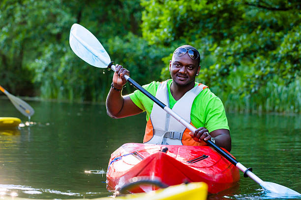 African Man paddling with canoe on forest river
