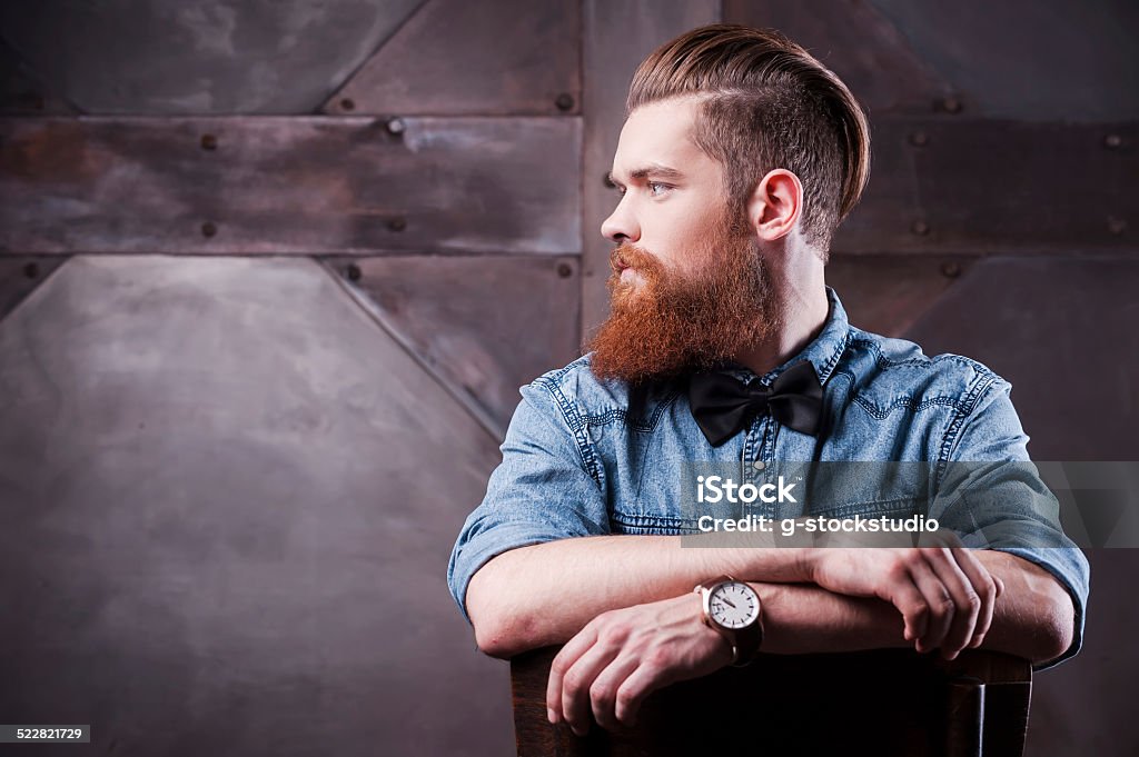 Confident in his perfect style. Profile of a handsome young bearded man looking away and sitting on chair 20-29 Years Stock Photo