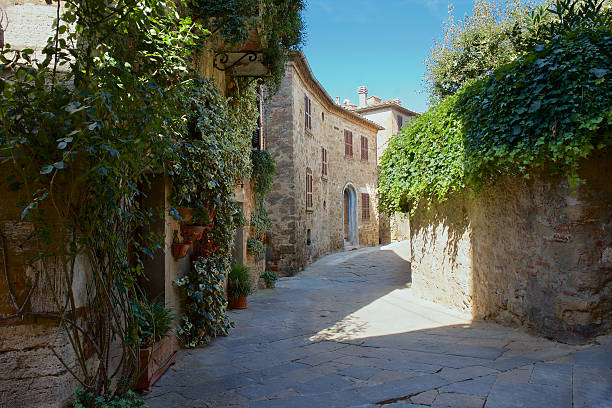 The ancient hilltop city of Pienza, Tuscany, glows in the warm light of the golden hour. The view from the city wall showcases the charming stone buildings overlooking the rolling hills of the Tuscan countryside, creating a picturesque scene.