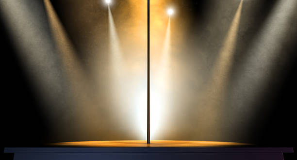 Stripper Pole Spotlit An isolated stripper pole on a stage lit by an array of spotlights on a dark background strip club stock pictures, royalty-free photos & images
