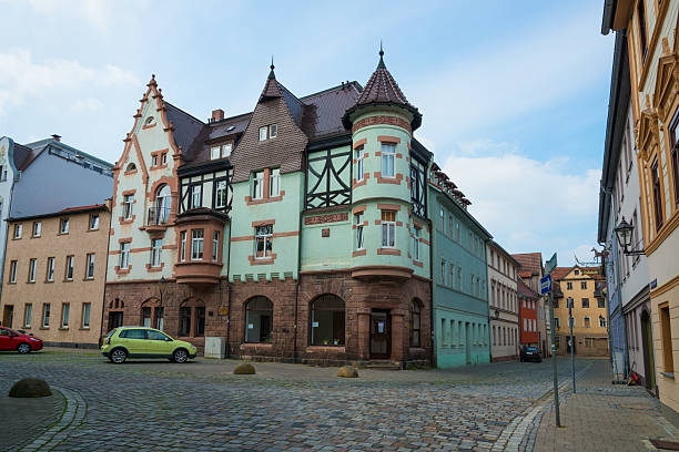 the Karl Liebknecht place in Kahla - Thuringia, Germany. Kahla is located in the near of the Leuchtenburg. Its a new restaurated small city with a very nice colorful old town. Some cars parking at the market place and some people sitting in small restaurants.  Kahla is known for his famous porcelain manufacture.