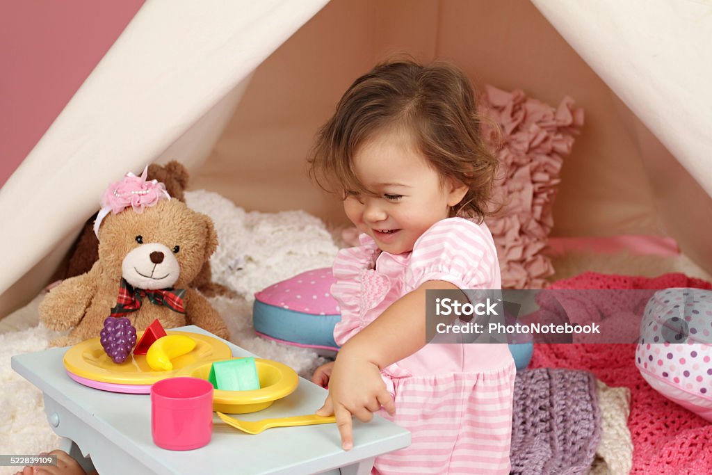 Pretend Play Tea Party at home with a TeePee Tent Happy toddler girl engaged in pretend play tea party indoors at home with a teepee tent Asian and Indian Ethnicities Stock Photo