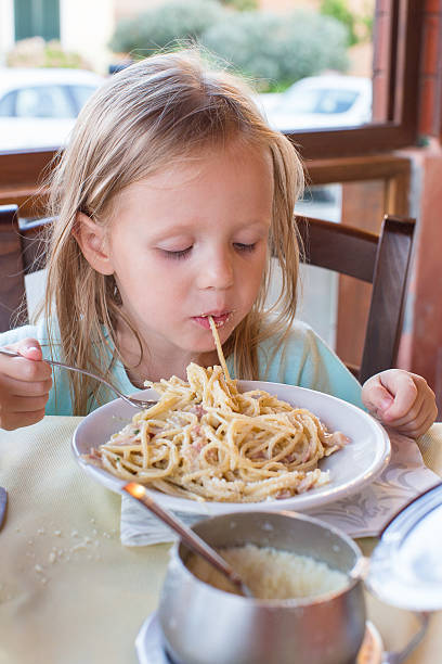 istock Adorable little girl eating spaghetti in outdoors restaraunt 522852017