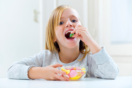 Portrait of beautiful child eating sweets at home.