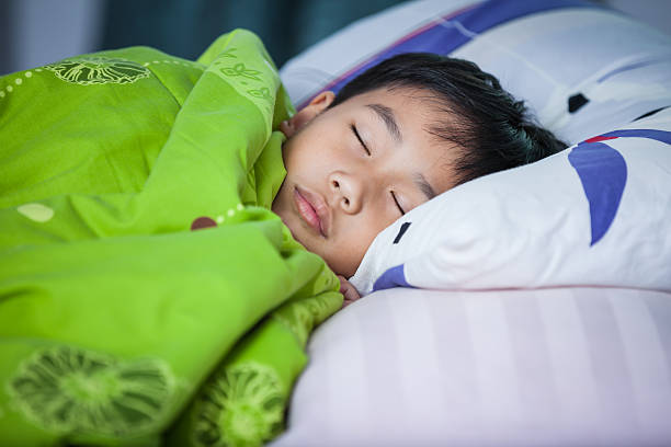 Healthy child. Little asian boy sleeping peacefully on bed. stock photo
