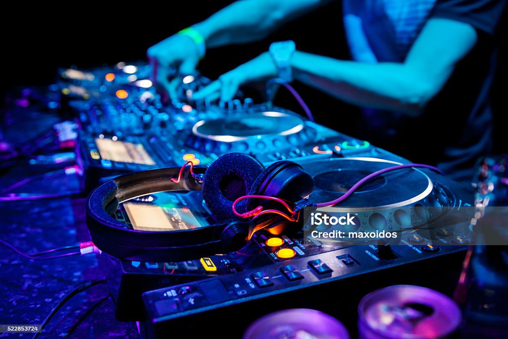 Dj playing the track Dj mixes the track in the nightclub at party. Headphones in foreground and DJ hands in motion DJ Stock Photo