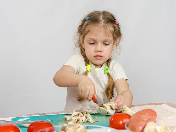 istock Five-year girl at the table hard cuts mushroom knife 522853868