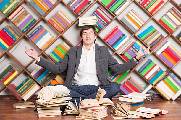 istock meditating man in the library with books on head 522854012