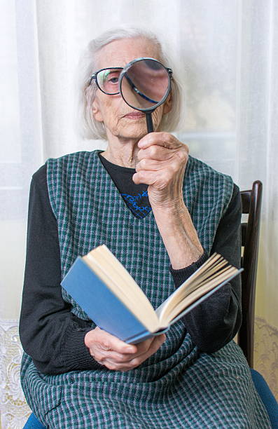 istock Grandma reading a book through magnifying glass 522857978