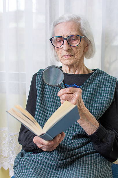 istock Grandma reading a book through magnifying glass 522858058