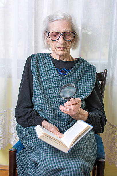 istock Grandma reading a book through magnifying glass 522858140
