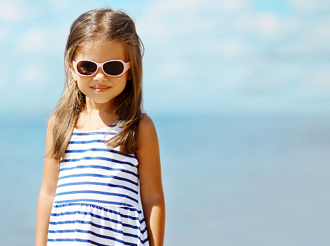 Summer, vacation, travel and people concept - portrait little girl in sunglasses near sea