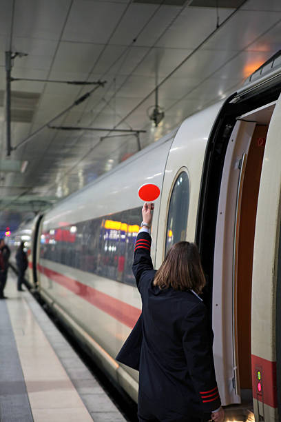 Young girl with hat on her head with luggage with hand up waiting for train