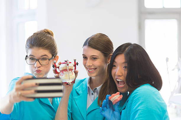 Playful female students learning prosthetic dentistry, taking selfie