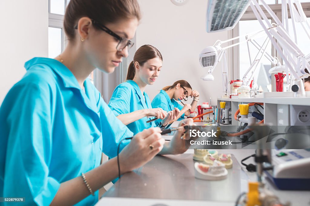 Female students learning prosthetic dentistry Female students wearing uniforms in a prosthodontic lab, learning prosthetic dentistry. Laboratory Stock Photo