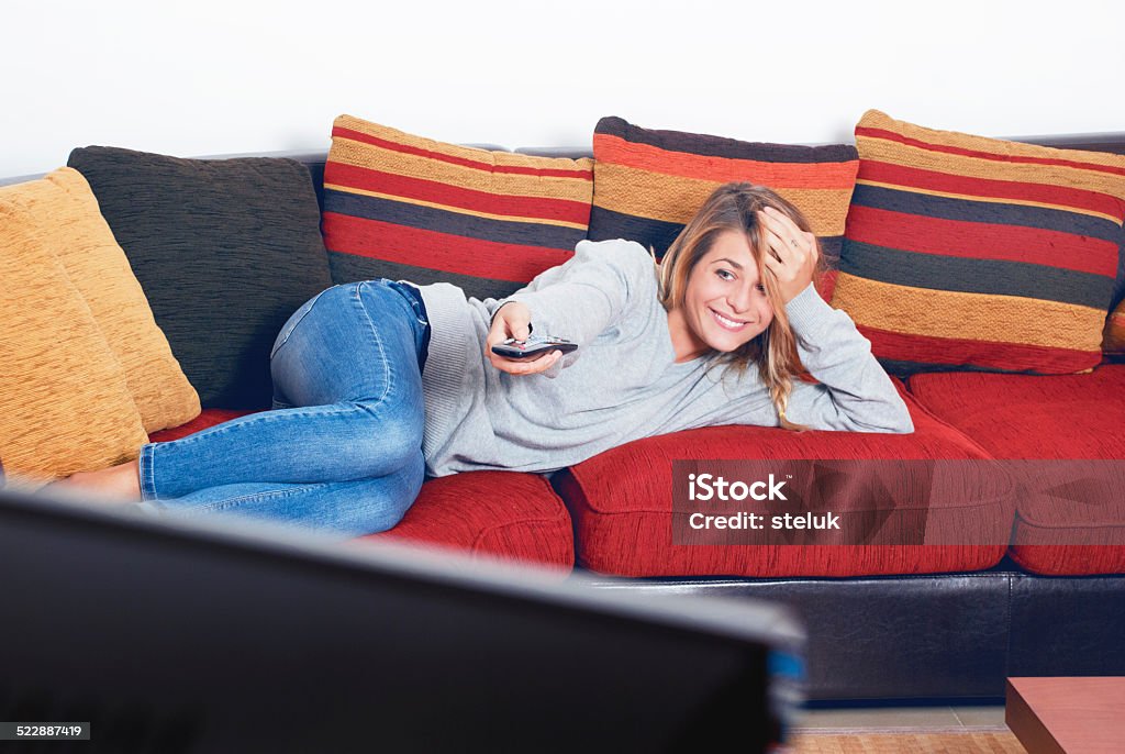 Smiling girl is watching tv Adult Stock Photo