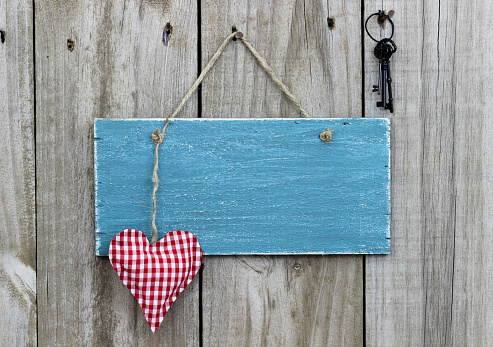 Antique blue sign with heart and keys hanging on door