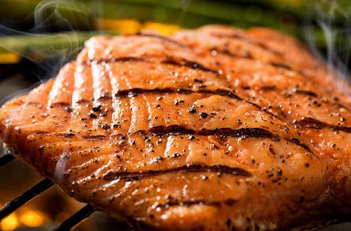 Close up of a grilled salmon filet on charcoal grill with asparagus, hot charcoal, fire and smoke.  Please see my portfolio for other food and drink images.
