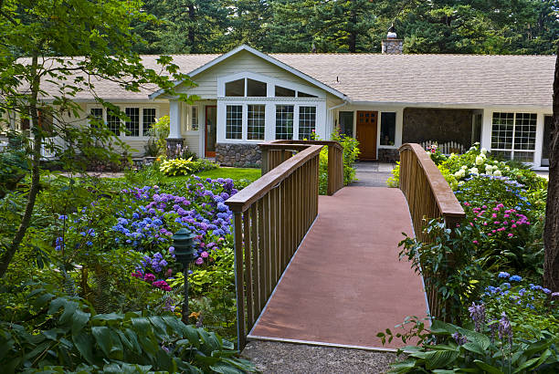 Bridge leads to Ranch Home surrounded by colorful hydrangea Gardens stock photo