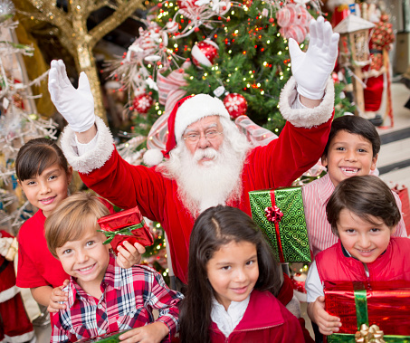 Santa Claus with a group of kids holding gifts