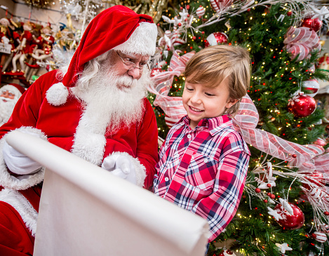 Santa with a kid showing him a Christmas shopping list