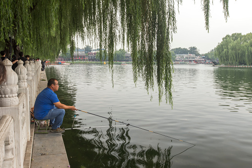 Beijing, China - September 12, 2014: One man are fishing at the houhai lake for pleasure.