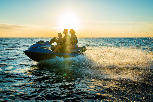 Young happy woman enjoying while riding jet boat in summer day at sea. Copy space.