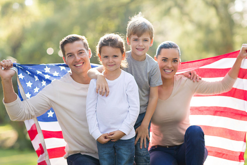 portrait of beautiful modern american family with USA flag outdoors