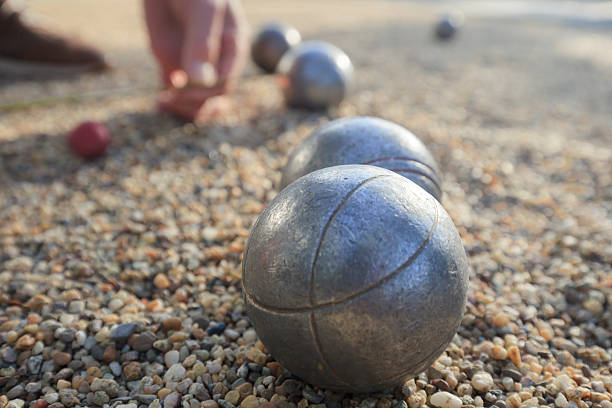 hand picking up a metallic petanque ball