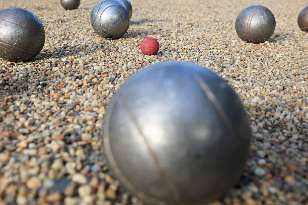Metallic petanque balls with shooting in action on the gravel.