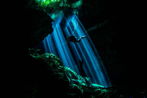 Rays of light in underwater caves Scuba diver exploring the underwater cenotes in Mexico near Puerto Aventuras. Caves are dark and the light always gives different amazing ambient underwater. puerto aventuras stock pictures, royalty-free photos & images