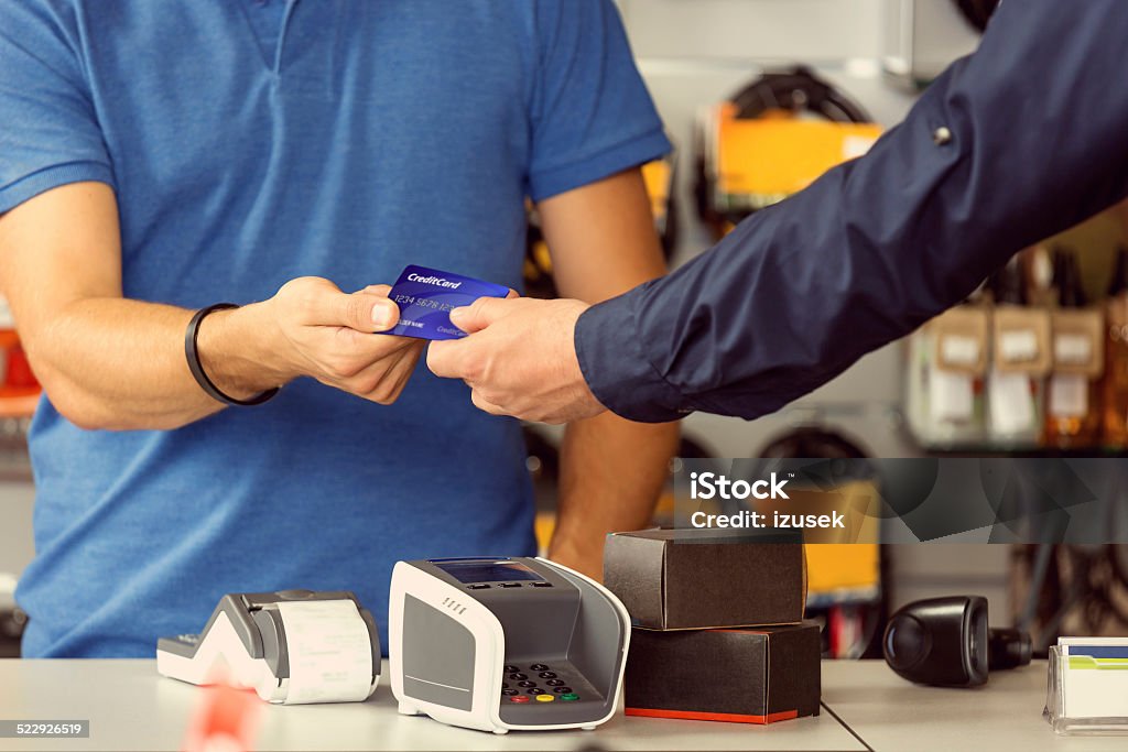 Paying by credit card Customer paying by credit card in a sport store. Focus on hands. Sports Shop Stock Photo