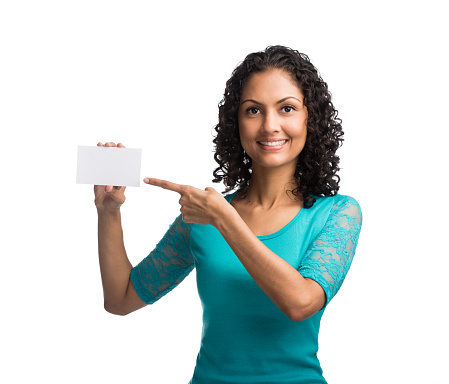 Woman pointing at empty business card and smiling isolated over white