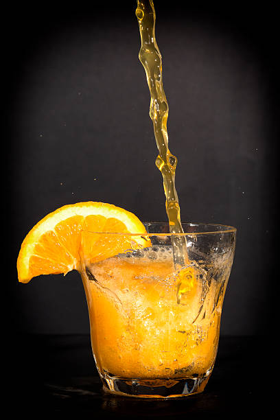istock Orange flavoured soft drink splashing over the glass. 522946571