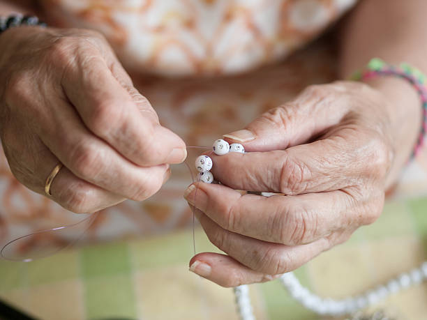 istock Hands of elderly woman threading a necklace 522947299