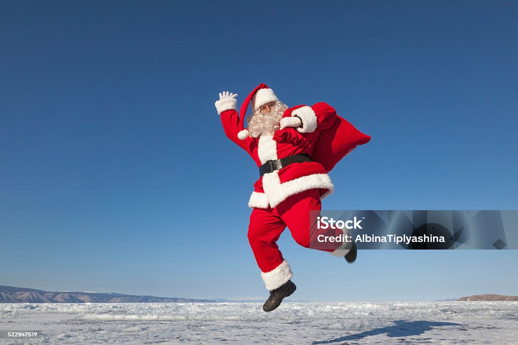 Jumping Santa Claus  outdoors Santa Claus joyously jumping in the snow,  shooting was conducted in a sunny day on lake Baikal Jumping Stock Photo