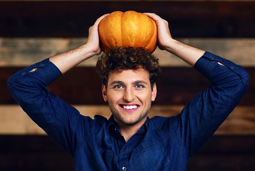 Portrait of a happy man with pumpkin on head