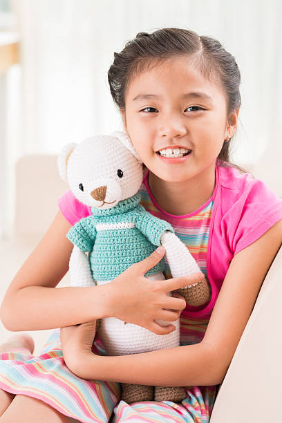 Girl with favorite toy Cute Vietnamese little girl holding handmade knitted bear vietnamese girls for sale stock pictures, royalty-free photos & images