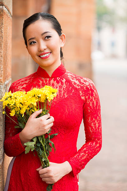 Beauty with flowers Beautiful Vietnamese woman in national red dress holding flower bouquet ao dai stock pictures, royalty-free photos & images