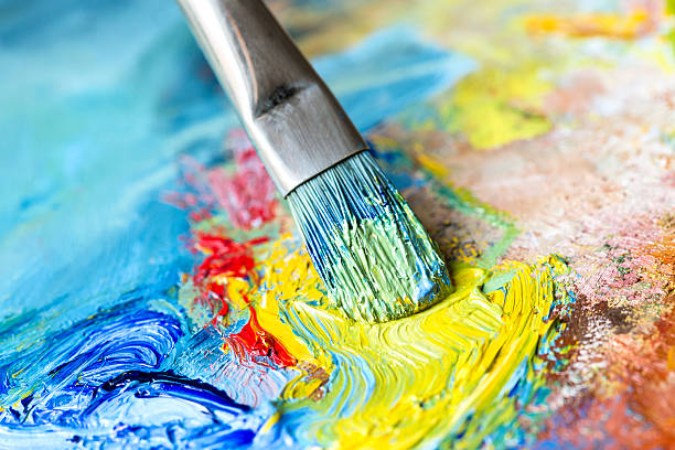 istock Paintbrush with yellow oil paint on a classical palette 522983619