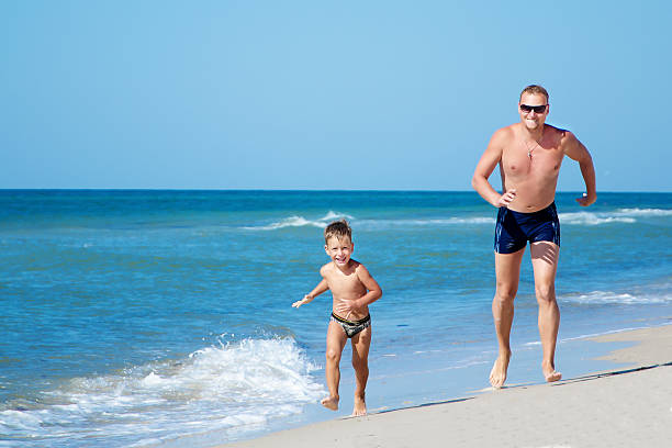 istock Happy father and his little sun running on beach 522984187