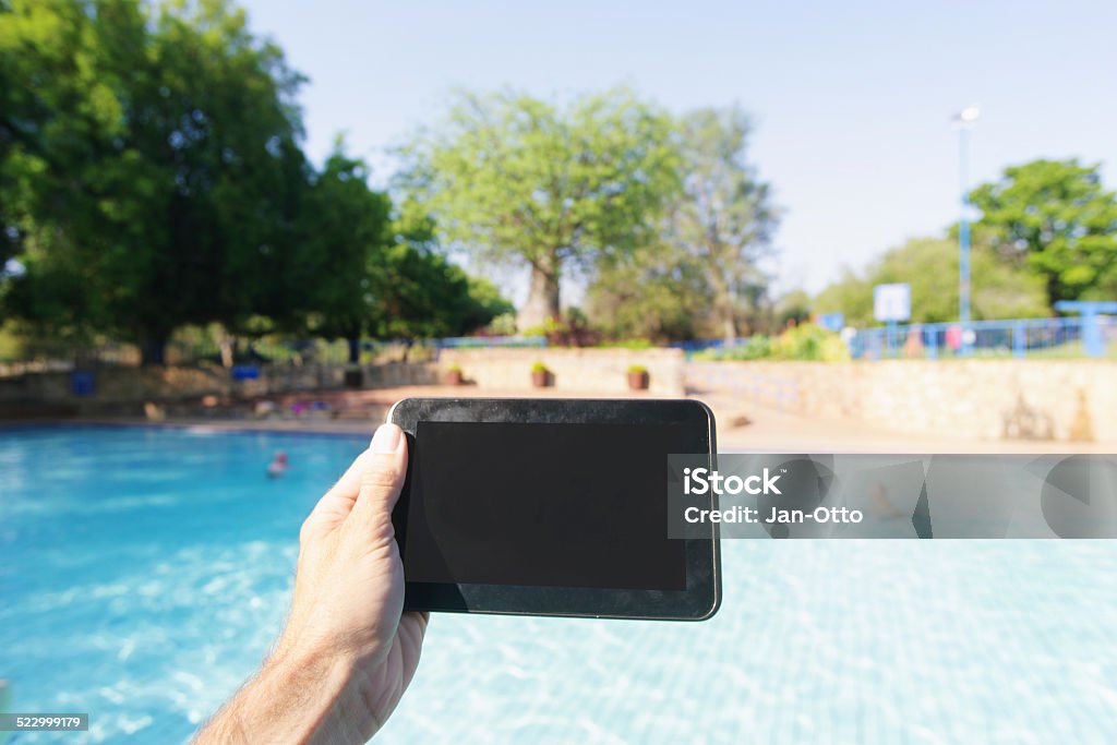 Holding tablet PC im Swimmingpool-Bereich - Lizenzfrei Gerätebildschirm Stock-Foto