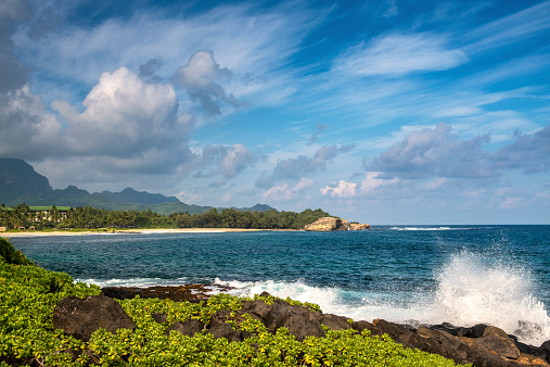 Shipwreck Beach in Po'ipu, Kaua'i, Hawai'i in October.  Waves crashing on the rocks throwing up spray.