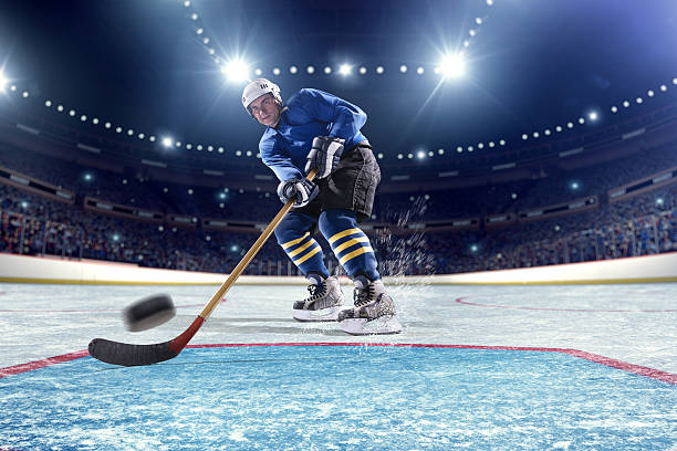 Ice Hockey Player Scoring Inside gates view of professional ice hockey player scoring during game in indoor arena full of spectators. hockey skates stock pictures, royalty-free photos & images