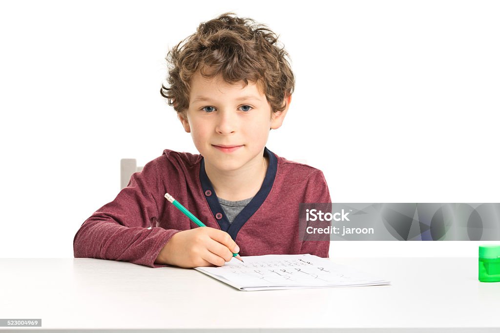 one 7 years old boy doing homework 7 years old school doing homework isolated on white Writing - Activity Stock Photo