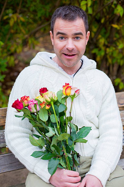 istock man sitting on a bench with roses 523005529