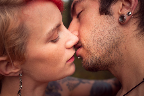 A tender moment of love as two real people share their first kiss. Selective focus on girl's eye.