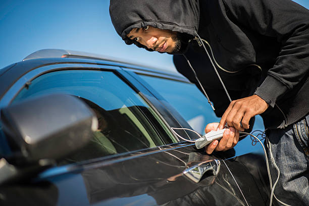 Black guy trying to open car's door with some kind of remote controlled equipment.   