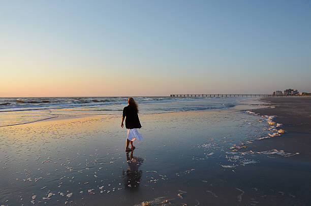 istock Girl walking on the beach at sunrise. 523029698
