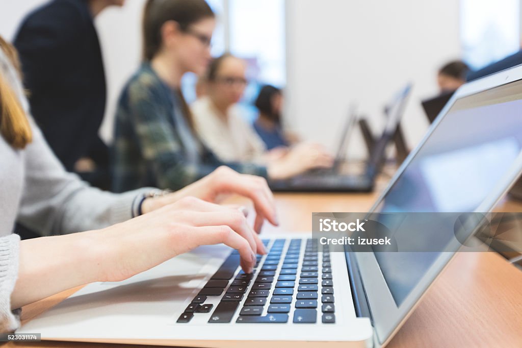 Female students learning computer programming Group of female students coding on laptops in a computer lab. Close up of hands and laptop keyboard. Laptop Stock Photo